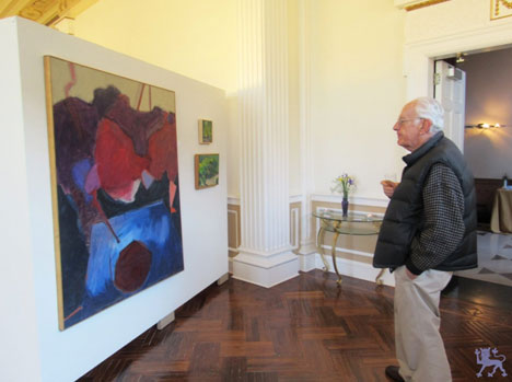 Patron viewing InnerVisions artworks. (Left by Jean Blumberg: To the Moon, Top right by Susan Leshnoff: Promenade, Bottom Right by Susan Leshnoff: Summer Path.)